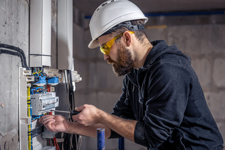 An electrician working on a switchboard while also learning about the importance of SEO for electricians
