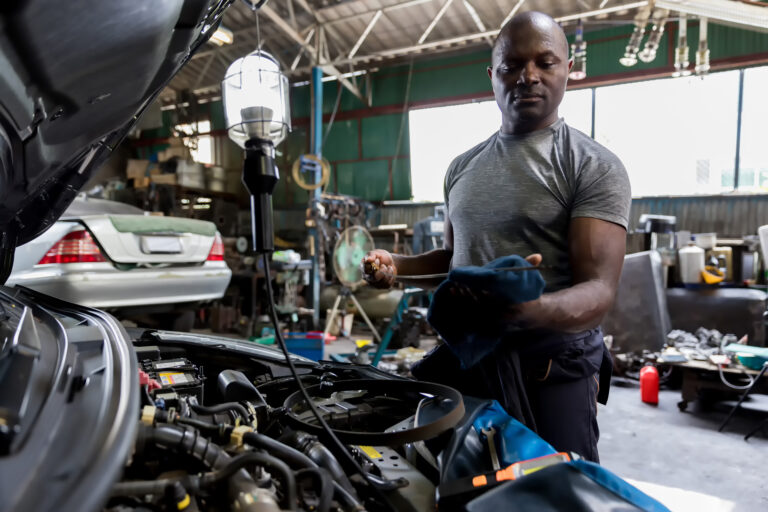 Mechanic checking oil in car and learning about the importance of seo for auto shops
