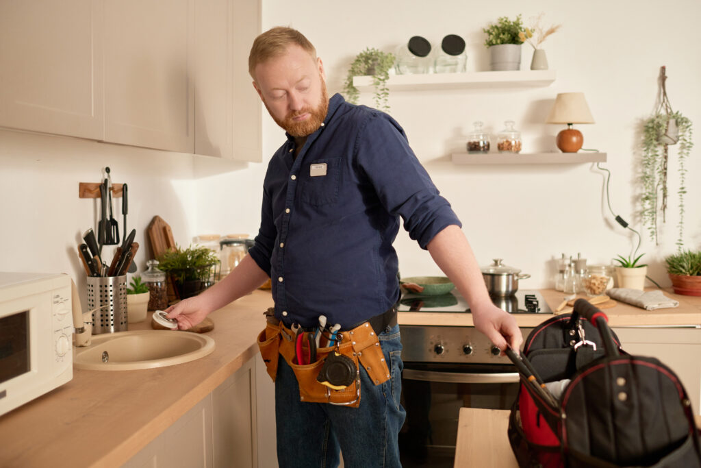 A plumber working on fixing a sink while also learning about the importance of SEO for plumbing